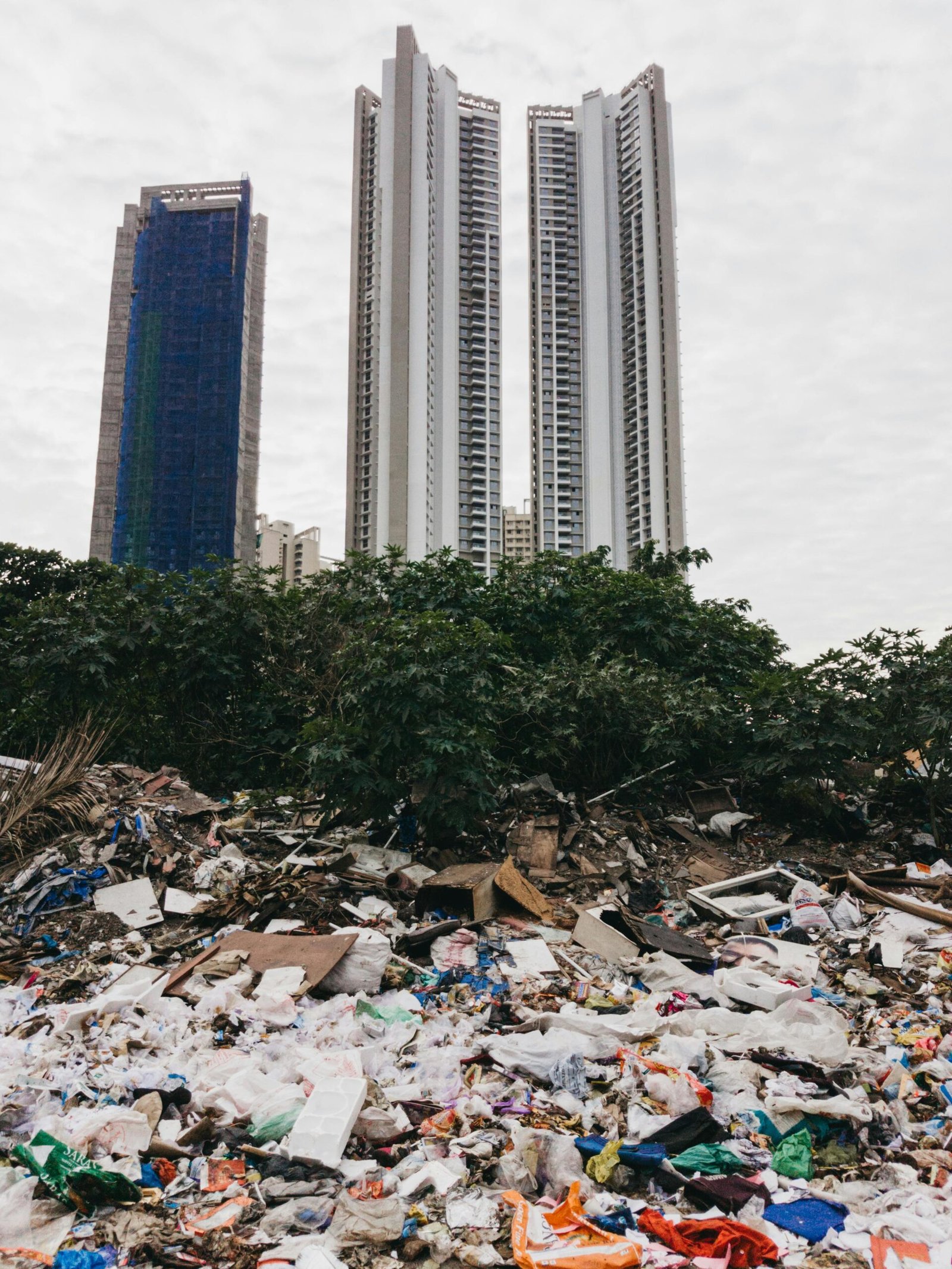 A large pile of trash in front of towering city skyscrapers symbolizes environmental neglect.